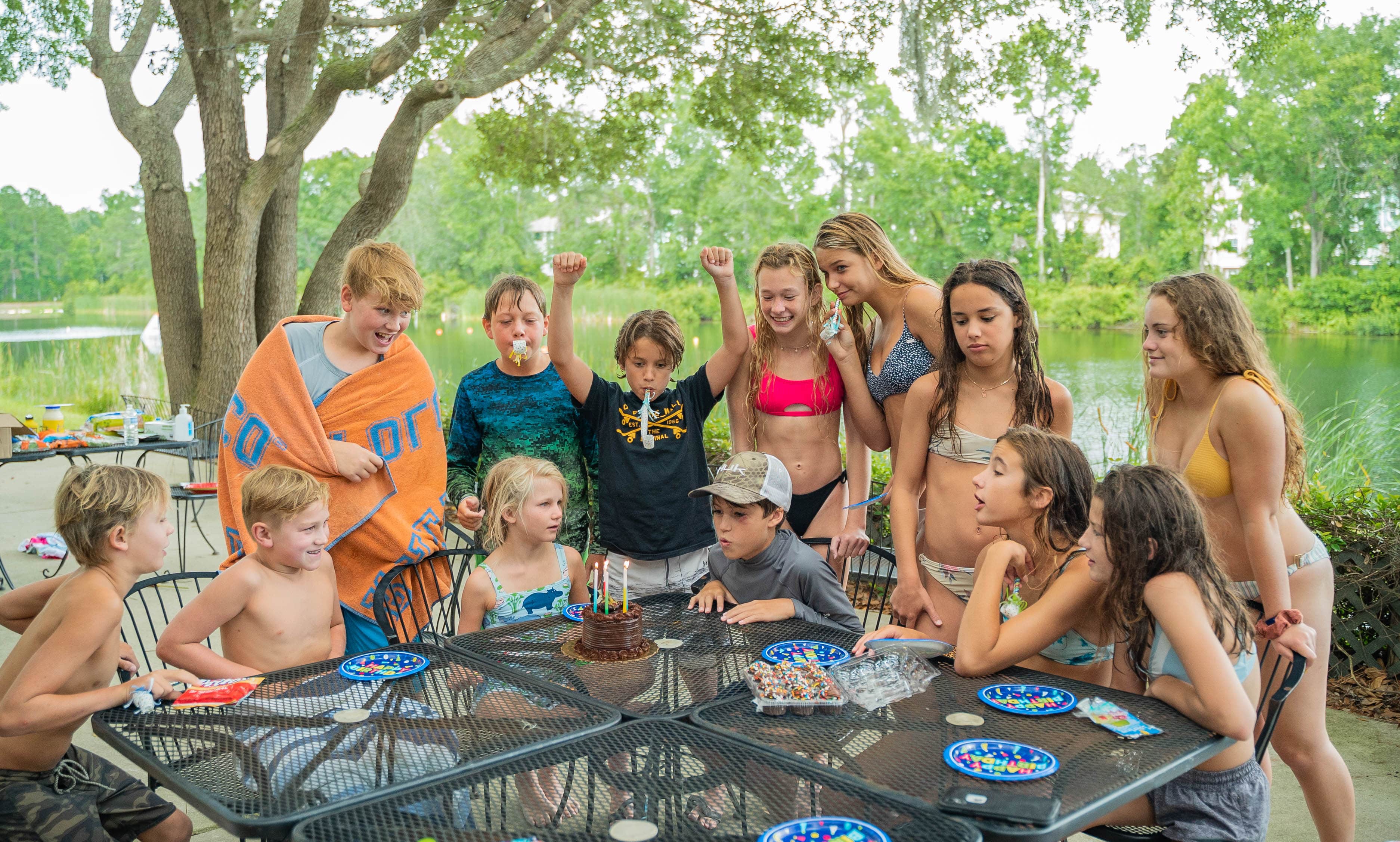 Bunch of happy kids staying in front of a table with cake